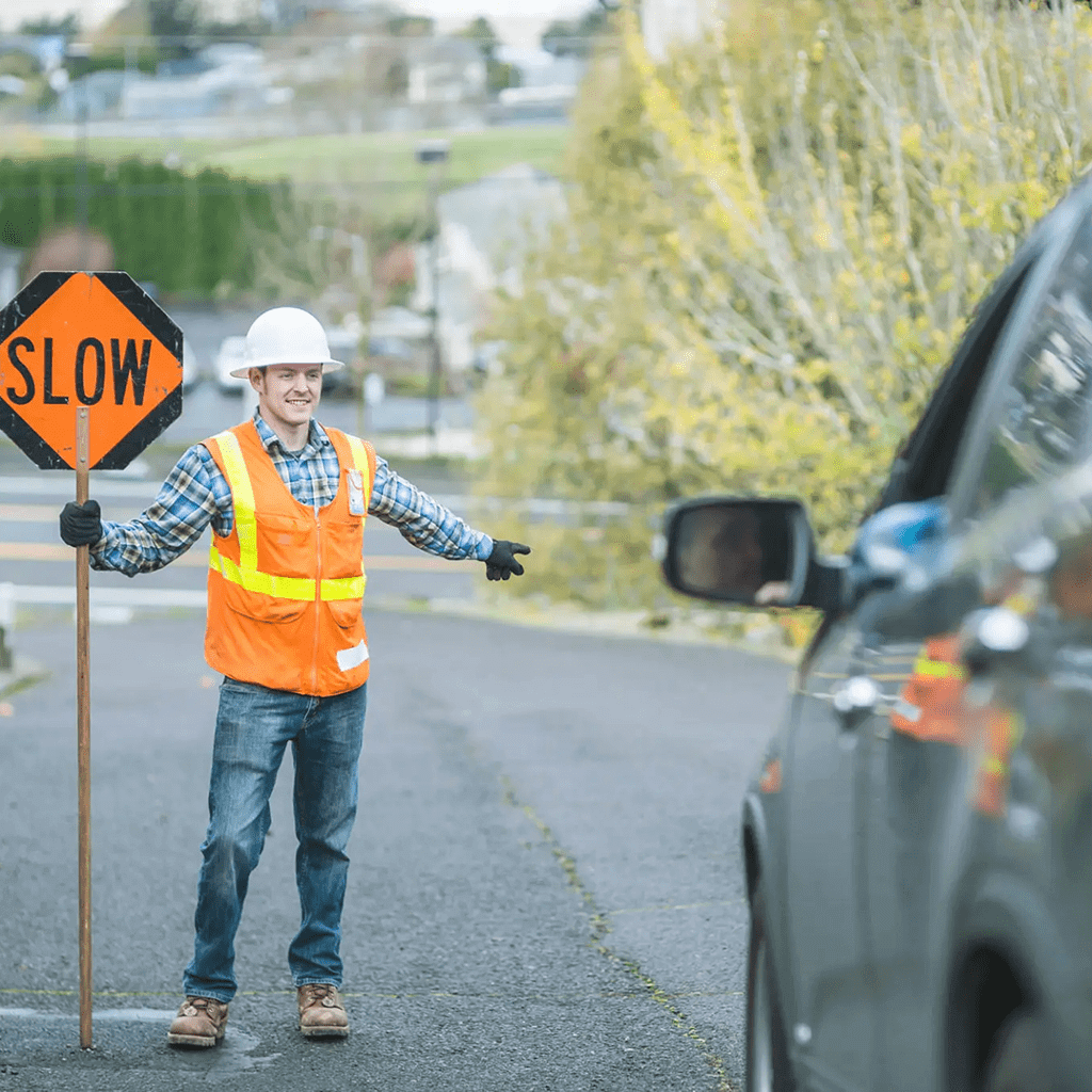 Construction worker holding a slow sign directing traffic.