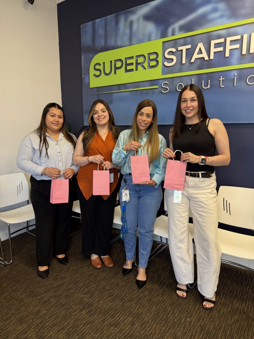 Four smiling women holding pink gift bags