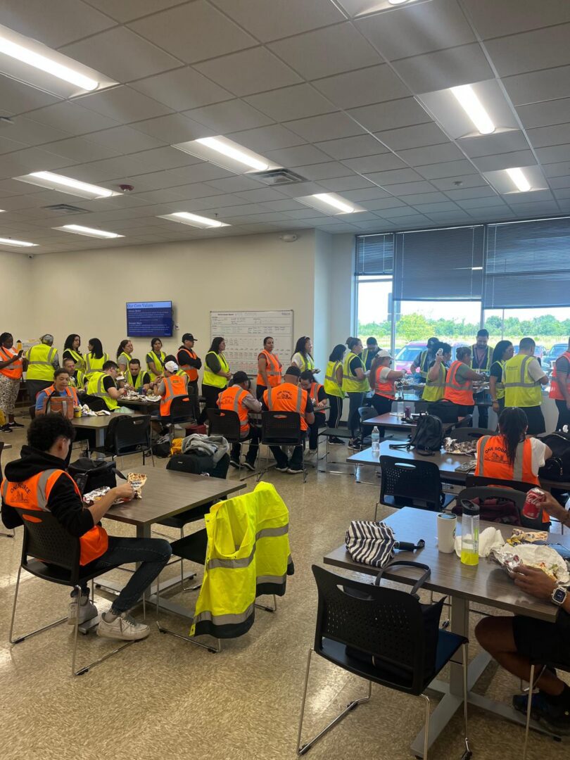 Workers in high-visibility vests eating in cafeteria