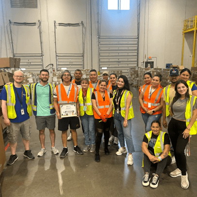 Group of people wearing safety vests in a warehouse.